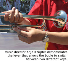 Music director Anja Knupfer demonstrates the lever that allows the bugle to switch between two different keys. Photo by Marching.com